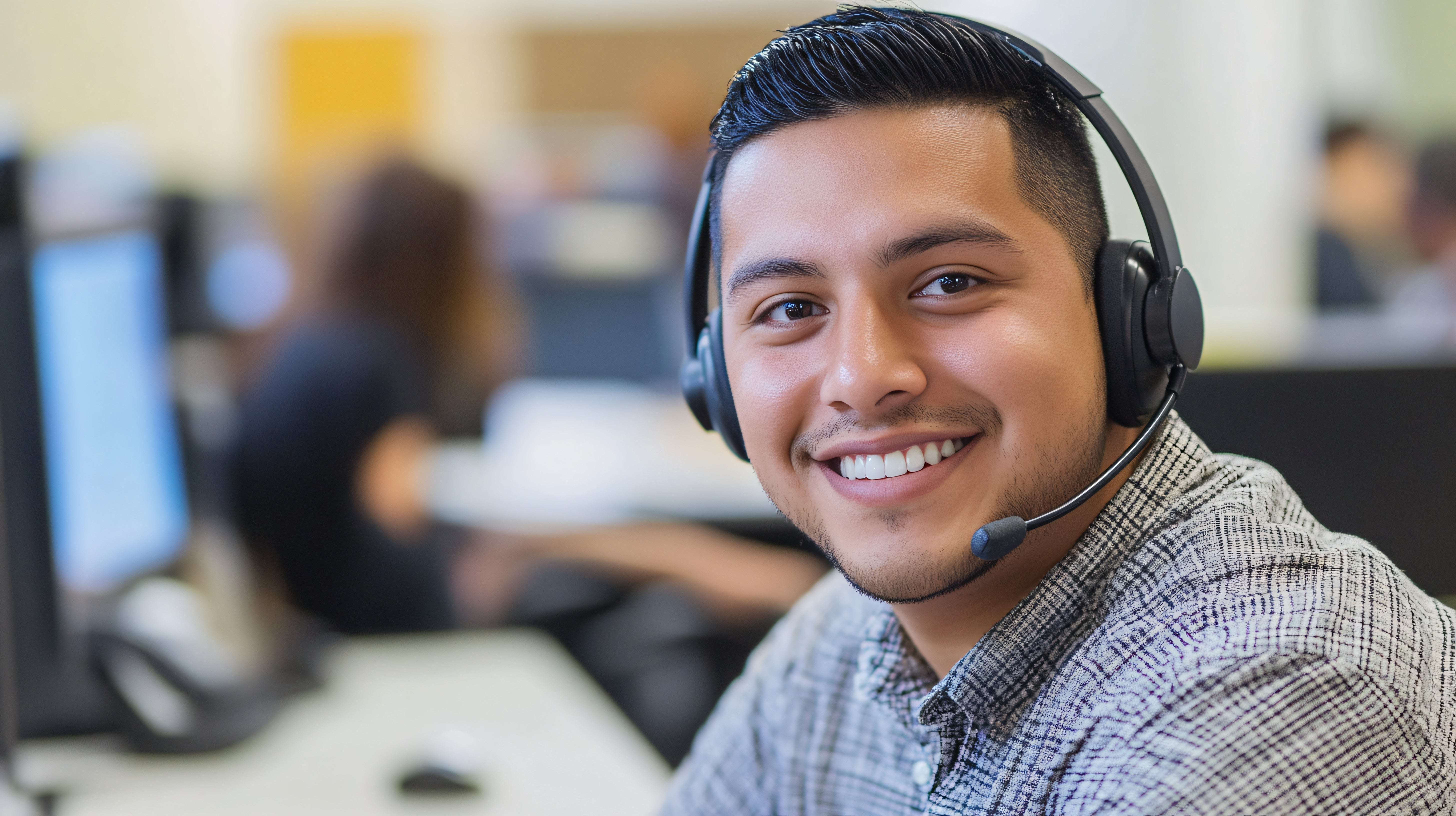 Young men wearing a headset and looking at the camera and smiling.